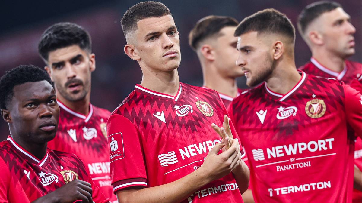 Pięciu piłkarzy w czerwonych strojach piłkarskich z białymi elementami "Newport", stojący obok siebie. Wszyscy patrzą w r&oacute;żnych kierunkach.