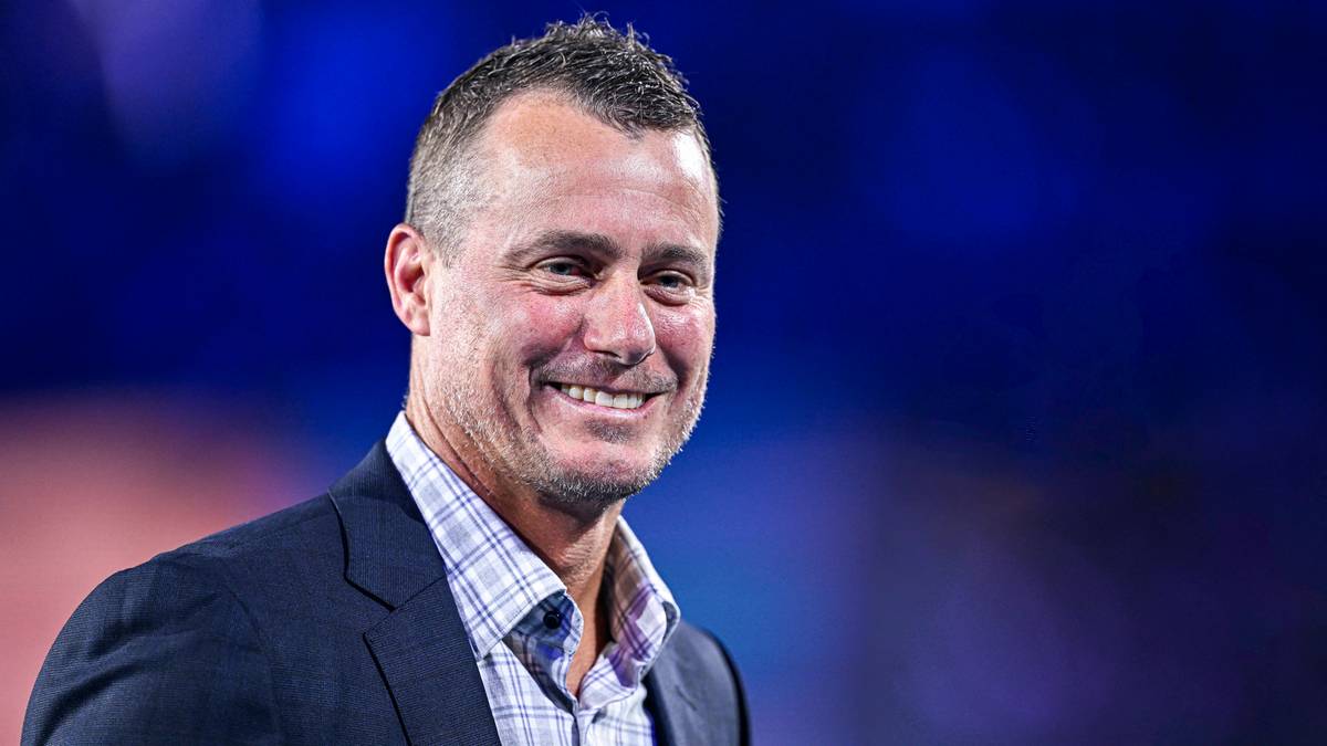 Lleyton Hewitt uśmiecha się do kamery, ubrany w marynarkę i koszulę w kratę.