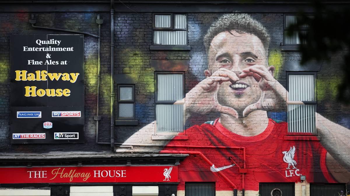Mural przedstawiający uśmiechniętego piłkarza Diogo Jotę w czerwonej koszulce Liverpoolu, wykonującego gest serca dłońmi.
