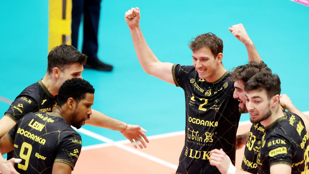 Grupa siatkarzy w czarnych strojach świętuje zwycięstwo na boisku.