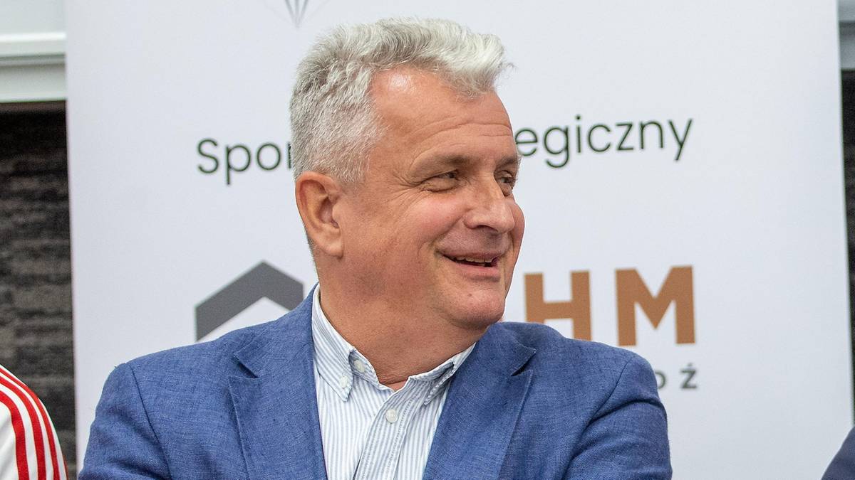 Dwóch mężczyzn w marynarkach siedzi przy stole, rozmawiając.