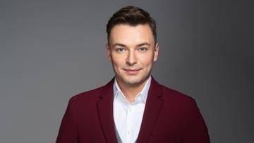 Eugeniusz Diaczkow w garniturze w kolorze burgunda, białą koszulą i szarą kamizelką.