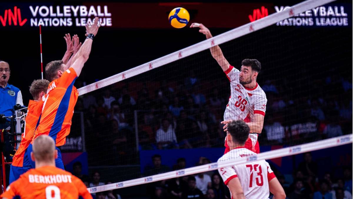 Gracz w białej koszulce z numerem 35 serwuje piłkę do siatkówki podczas meczu.