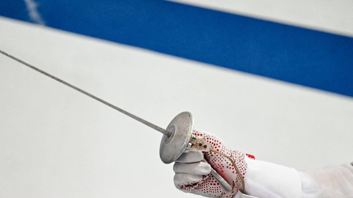 Dłoń w rękawicy szermierza trzymająca szpadę.