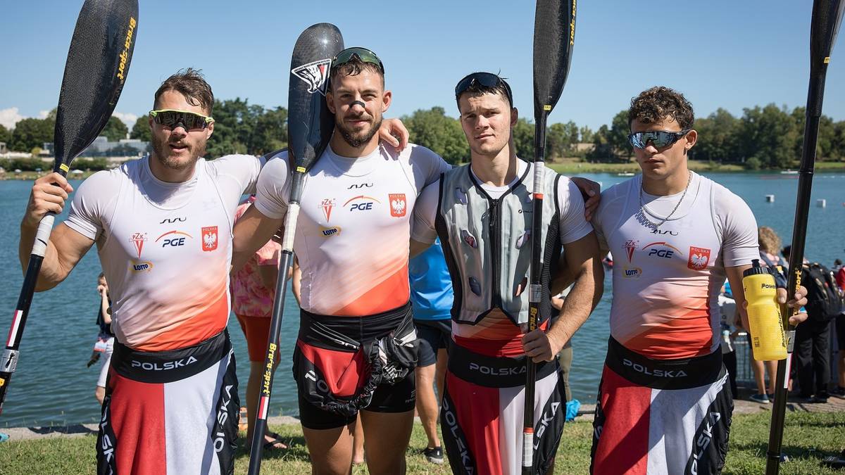 Czterech mężczyzn w strojach sportowych z logiem PKO BP, w Nachdem zawodach, pozuje do zdjęcia z kajakami.