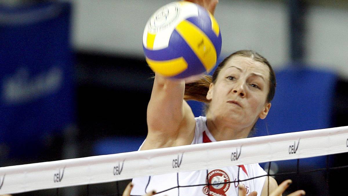 Siatkarka w białej koszulce z numerem 7 atakuje piłkę nad siatką.