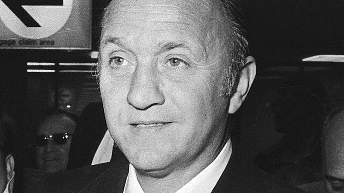 Portret mężczyzny w garniturze i krawacie, z wyraźnie zaznaczonymi rysami twarzy.