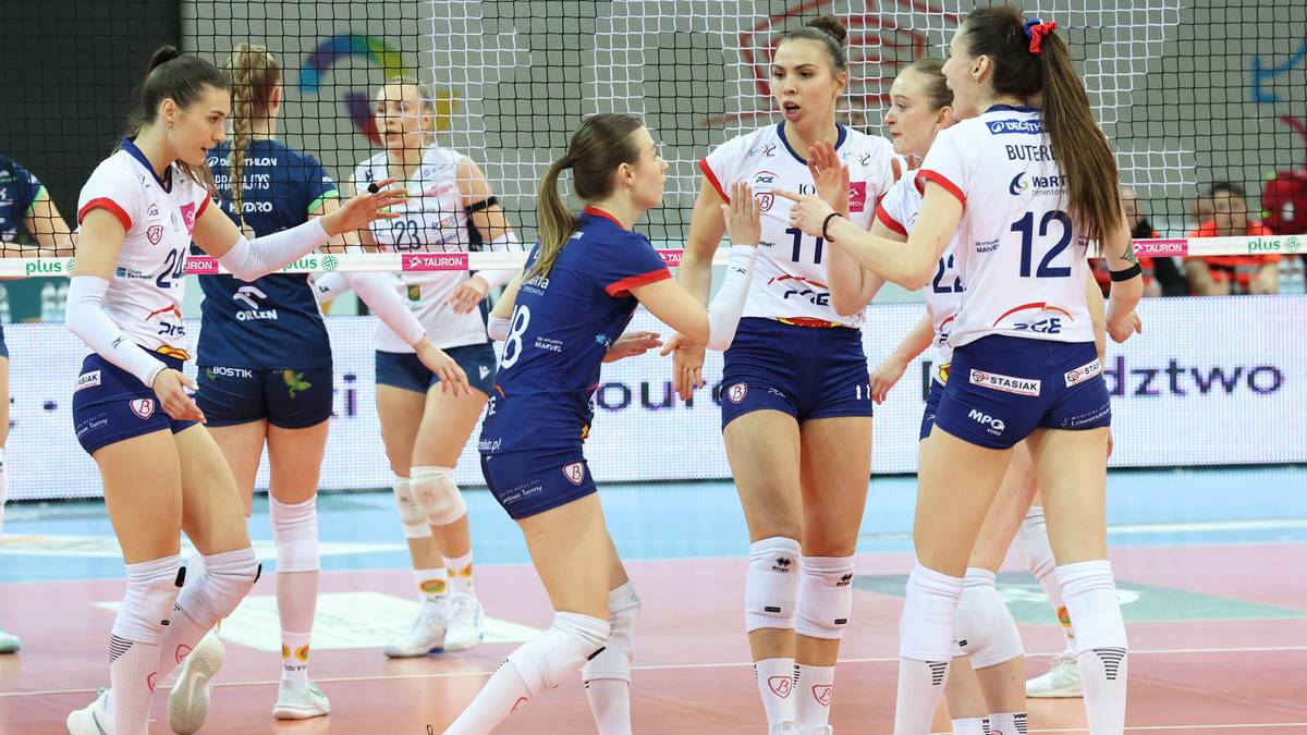 Sześć siatkarek w strojach sportowych na boisku do siatk&oacute;wki, w tle trybuny