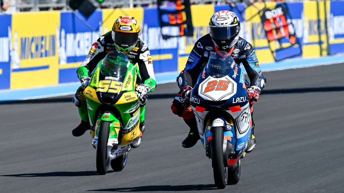 Dwóch motocyklistów ścigających się na torze, jeden na zielono-żółtym motocyklu, drugi na niebiesko-białym.