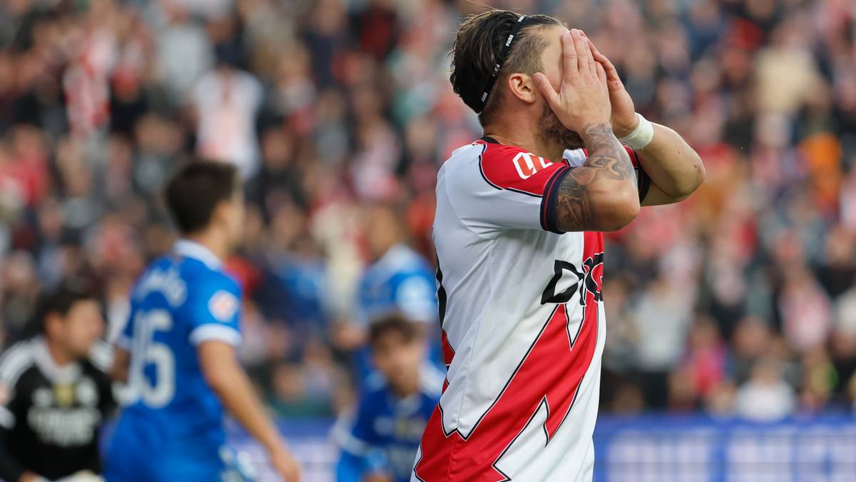 Piłkarz zakrywający twarz dłońmi podczas meczu.