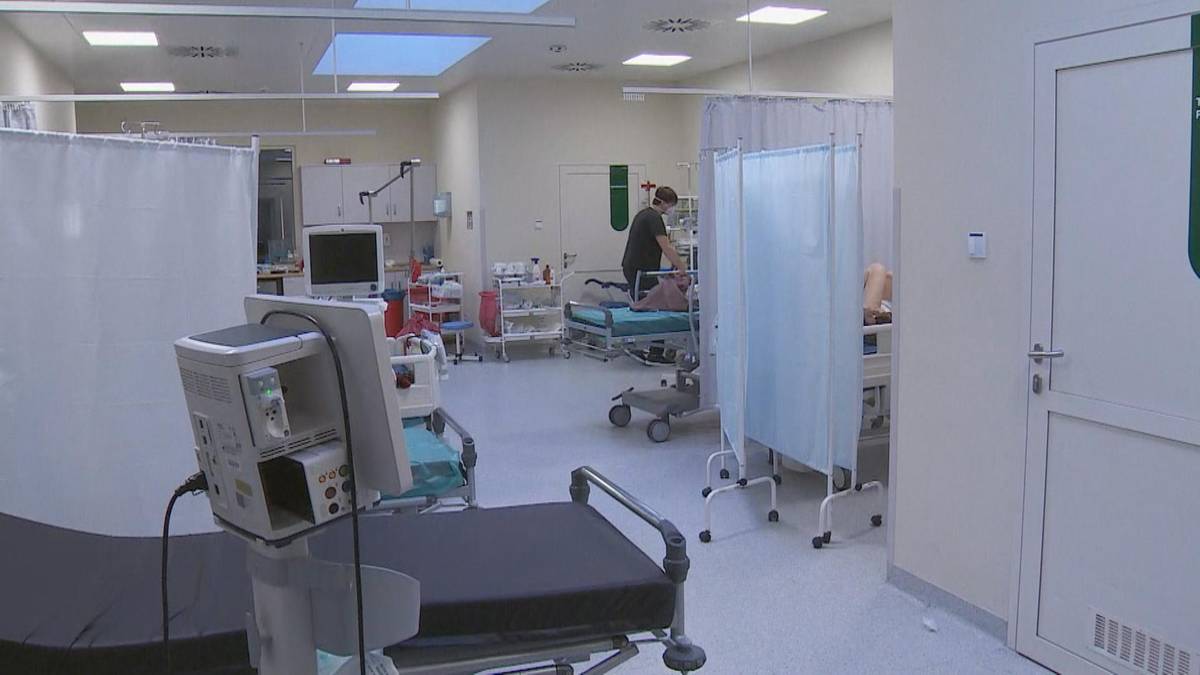 Wnętrze szpitalnego oddziału z ł&oacute;żkami i sprzętem medycznym.