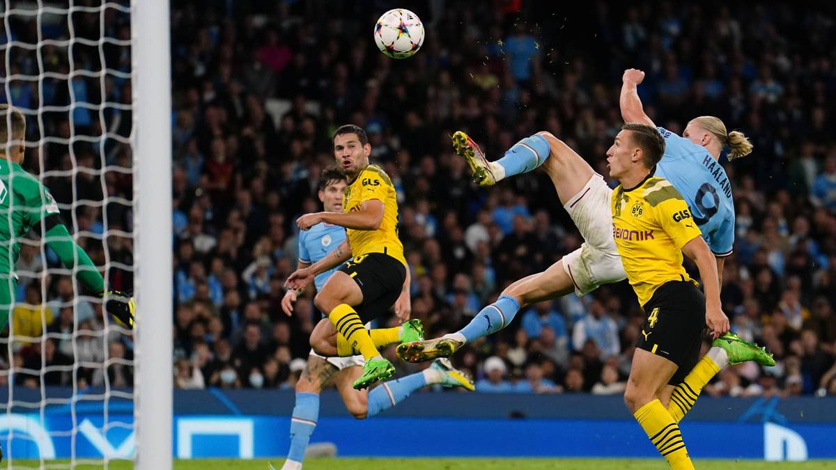 Piłkarze Manchesteru City i Borussii Dortmund rywalizują o piłkę na boisku.