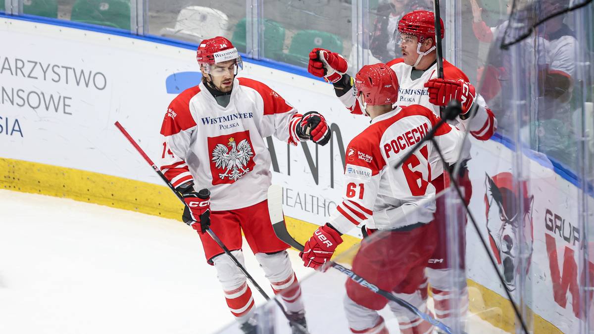 Trzech zawodników hokejowych w biało-czerwonych strojach świętuje zwycięstwo na lodowisku.