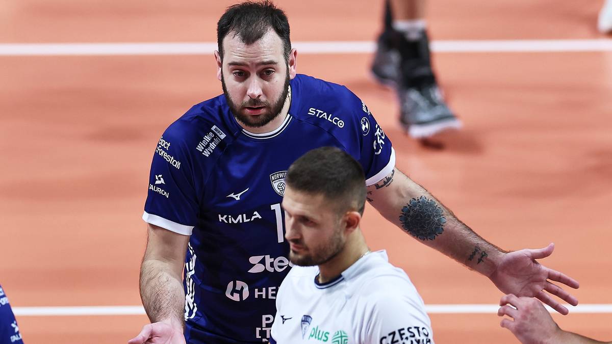 Dwóch siatkarzy dyskutuje na boisku, jeden w niebieskiej koszulce, drugi w białej.