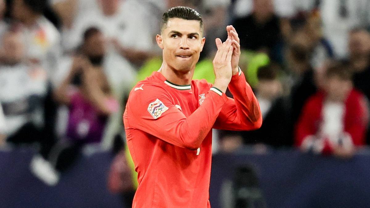 Cristiano Ronaldo w czerwonej koszulce, z dłońmi złożonymi w geście oklasków, na tle rozmytej publiczności.