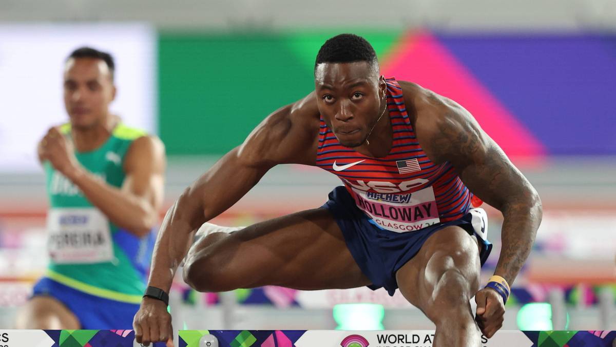 Murzyn biegnący przez płotki z wyraźnym wysiłkiem na twarzy.