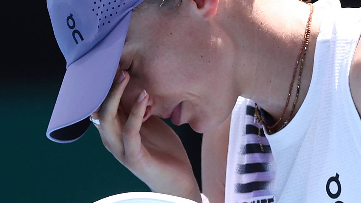 Tenisistka w czapce i z rakietą, zamyka oczy ręką.