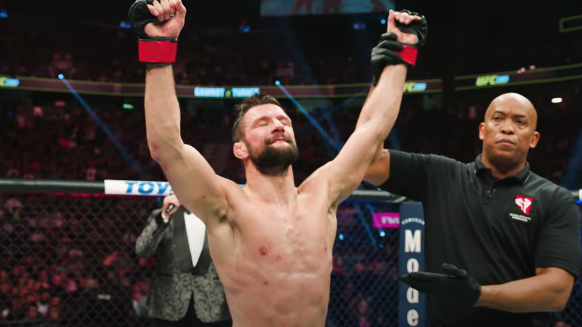 Sędzia podnosi rękę zawodnika MMA w geście zwycięstwa.