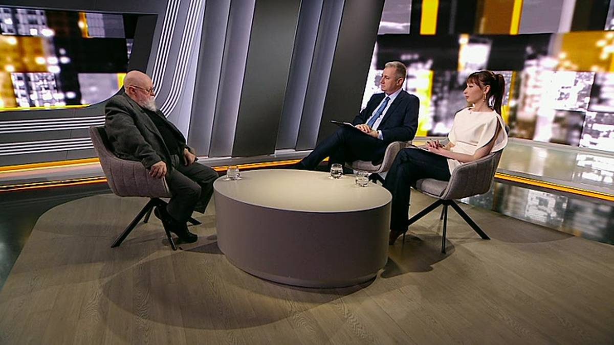 Trzy osoby siedzące przy okrągłym stoliku w studio telewizyjnym.