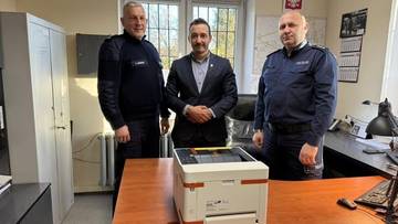 Trzech mężczyzn, w tym dw&oacute;ch policjant&oacute;w i burmistrz, pozuje do zdjęcia z nową drukarką przekazaną policji w Trzemesznie.