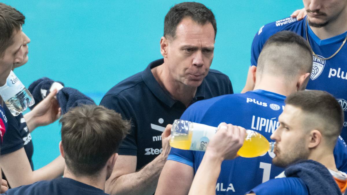 Trener siatkówki w mundurze podaje wodę zawodnikowi w niebieskiej koszulce z numerem 7.