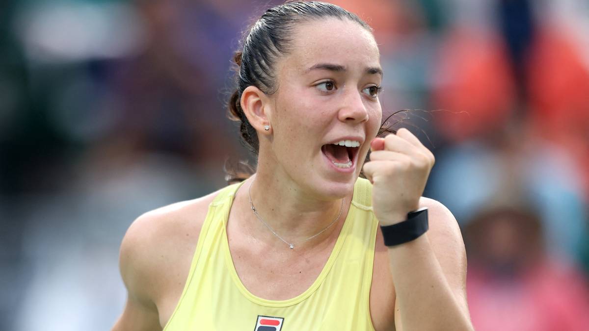 Młoda kobieta tenisistka w żółtym topie, zaciśniętą pięścią i wyrazem triumfu na twarzy, podczas meczu.