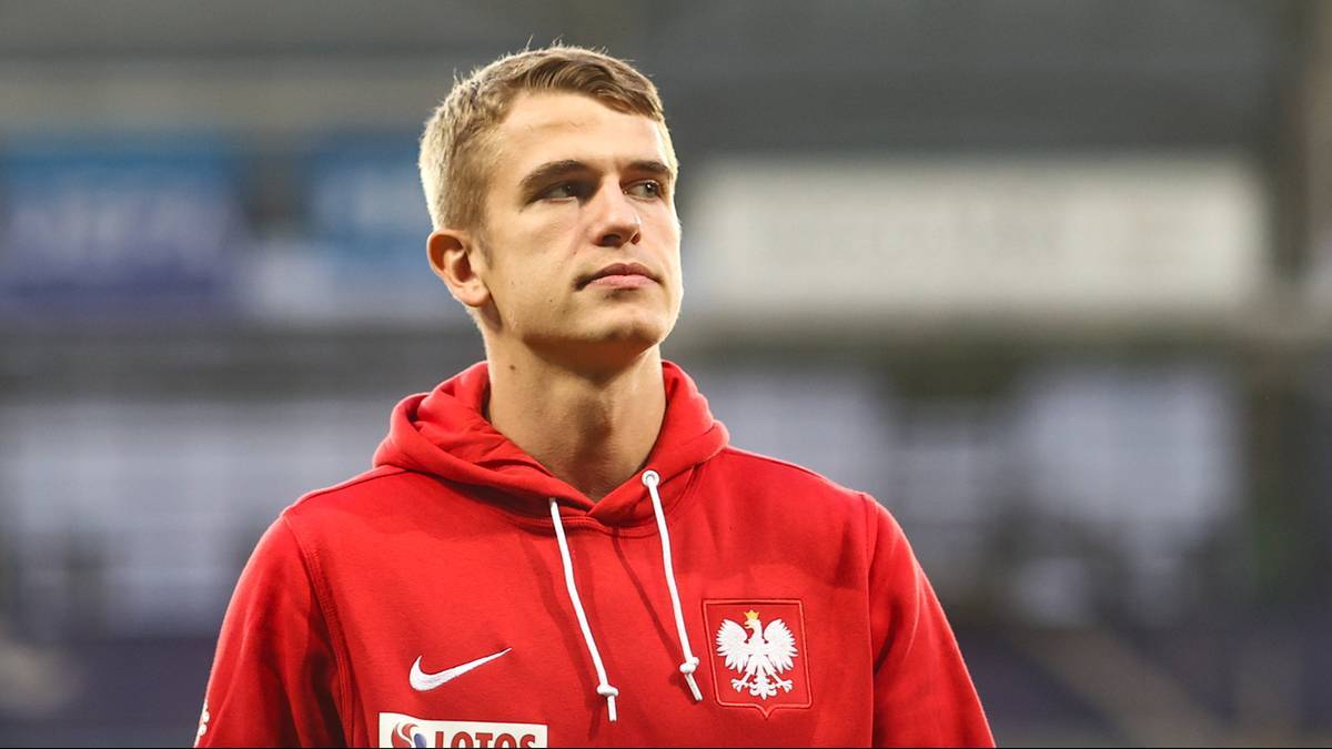 Piłkarz w czerwonej bluzie z polskim godłem patrzy w bok