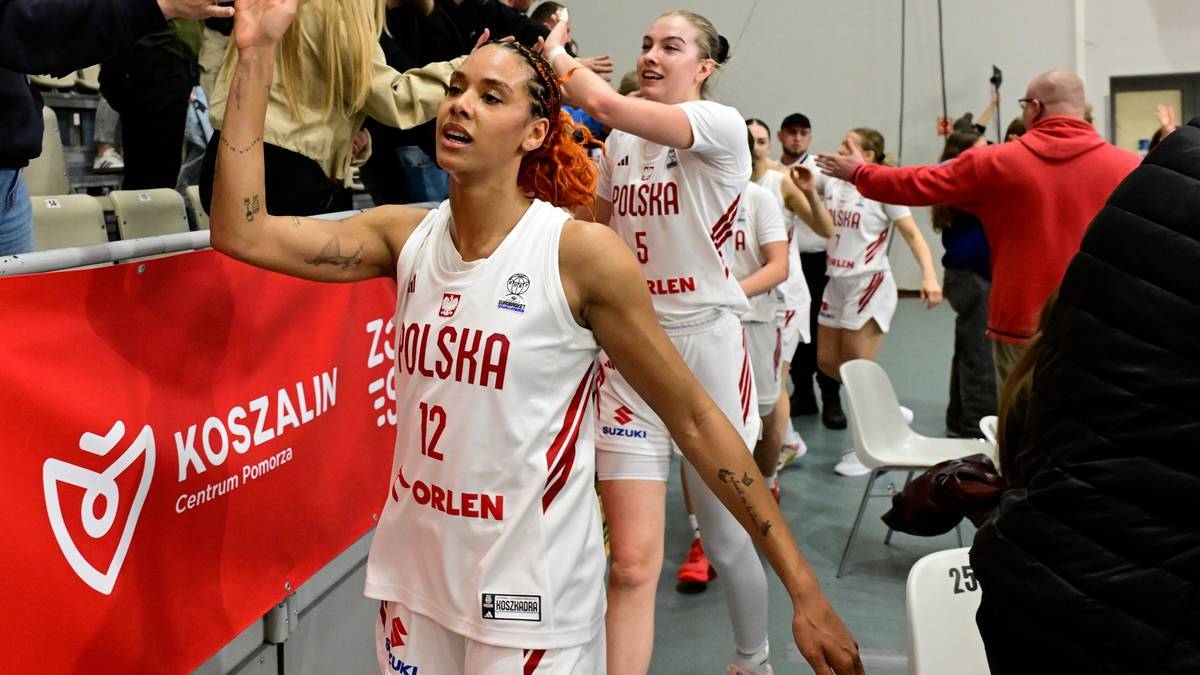 Dwie zawodniczki reprezentacji Polski w koszykówce w białych strojach z czerwonymi elementami, jedna z nich z numerem 12 na koszulce, macha do kibiców.