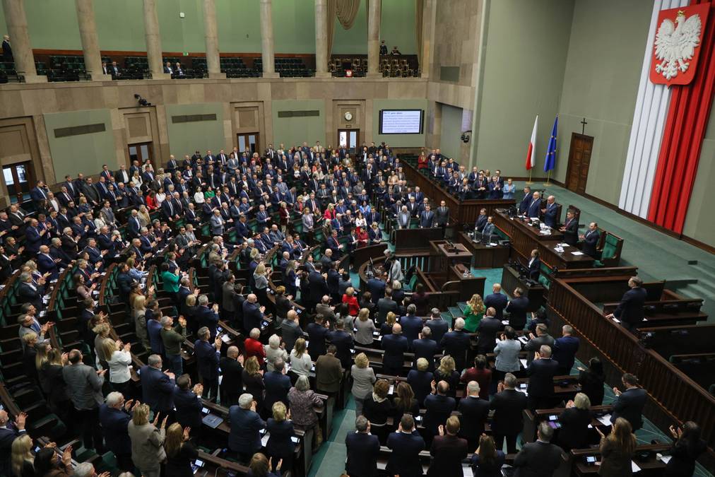 Posiedzenie Sejmu Rzeczypospolitej Polskiej, widok z góry na salę plenarną wypełnioną posłami siedzącymi w ławach.