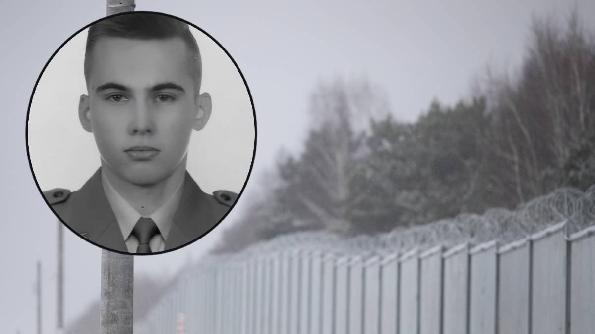 Zdjęcie przedstawia zbliżenie na twarz młodego mężczyzny w mundurze wojskowym w okręgu, na tle ogrodzenia z drutem kolczastym i zamazanych drzew.
