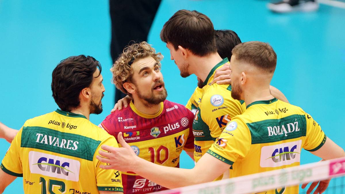 Grupa siatkarzy w ż&oacute;łtych strojach drużynowych rozmawia ze sobą na boisku siatkarskim.