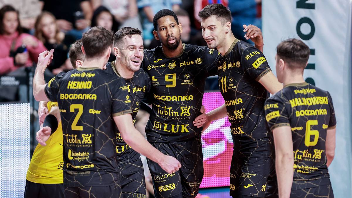 Grupa siatkarzy Bogdanki w czarnych strojach świętuje zwycięstwo na boisku.