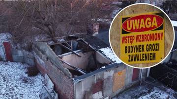 Zniszczony budynek z częściowo zawalonym dachem i tabliczką ostrzegawczą "UWAGA WSTĘP WZBRONIONY BUDYNEK GROZI ZAWALENIEM".