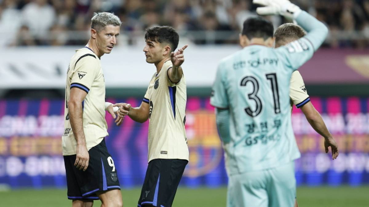 Piłkarze Robert Lewandowski i Gavi z FC Barcelony rozmawiają na boisku. W tle bramkarz w jasnej koszulce z numerem 31.