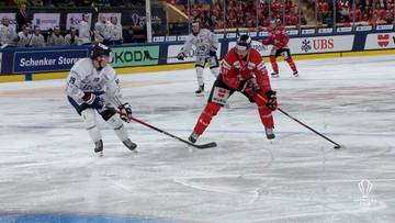 Dw&oacute;ch graczy hokejowych na lodzie podczas meczu, jeden w białym stroju, drugi w czerwonym, z kijami w rękach.