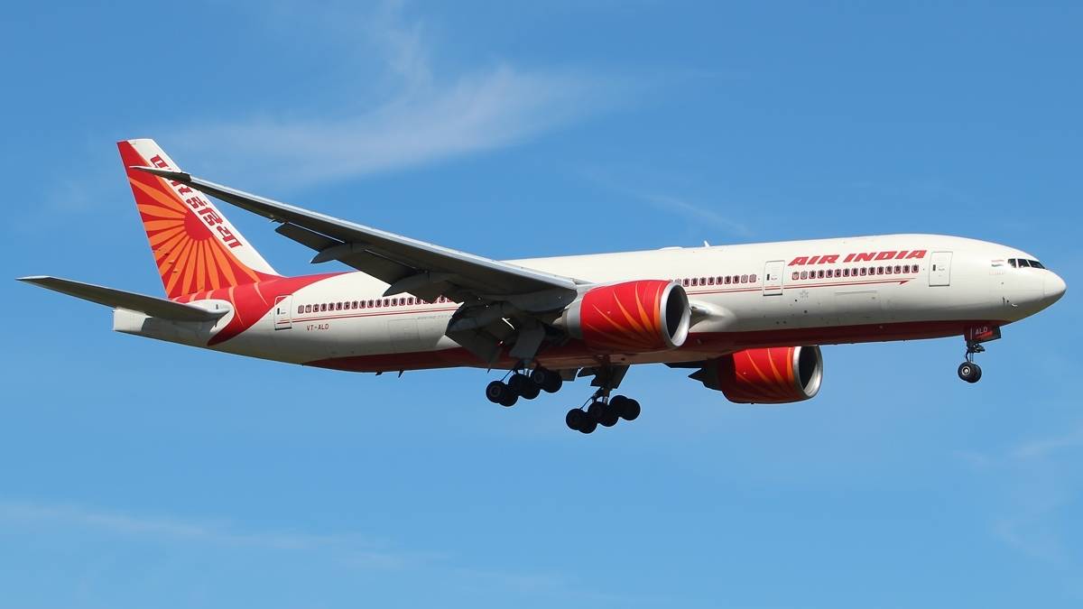 Samolot pasażerski linii Air India z czerwonymi elementami malowania na białym tle, w locie na błękitnym niebie.