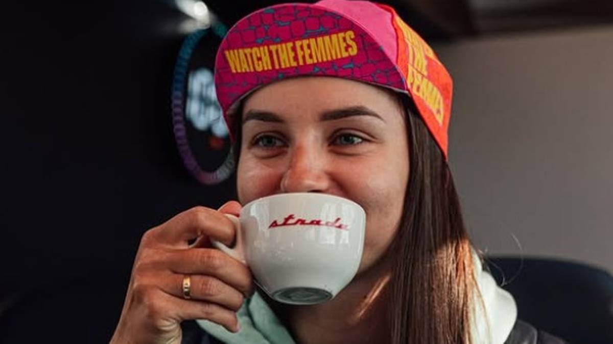 Kobieta w czapce kolarskiej pije kawę z białej filiżanki.