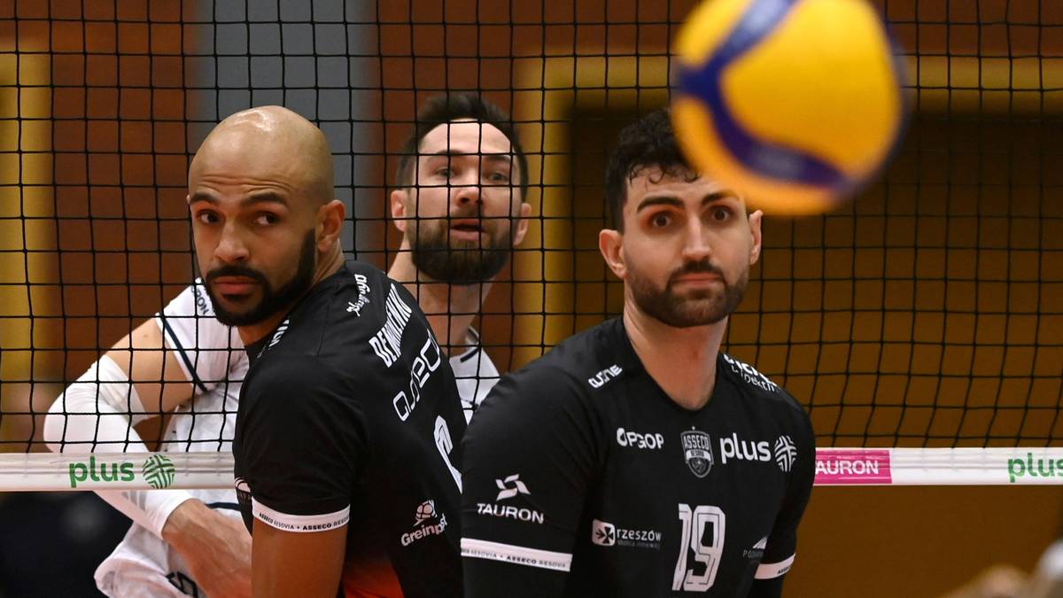 Siatkarze w czarnych strojach sportowych z numerami na koszulkach.