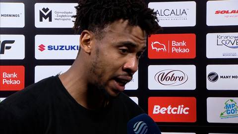 Paul Scruggs, koszykarz, udziela wywiadu na tle ścianki z logo sponsor&oacute;w.