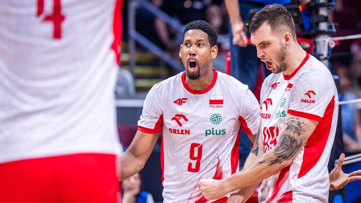 Dwóch siatkarzy w białych koszulkach z czerwonymi pasami, z numerami 9 i z częściowo widocznym numerem 4. Jeden zawodnik z numerem 9 ma otwarte usta w wykrzyknieniu, drugi patrzy w stronę sędziego.