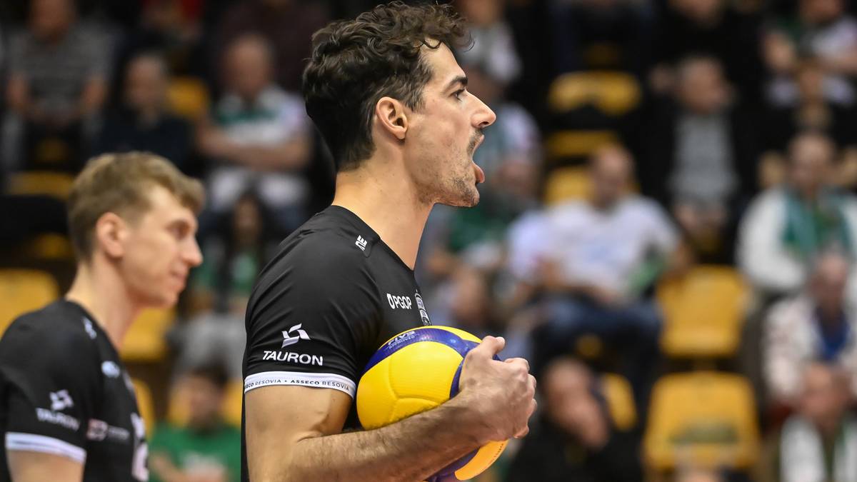 Siatkarz w akcji podczas meczu, trzymający piłkę.