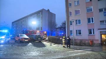 Akcja ratunkowa przed budynkiem mieszkalnym z obecnością woz&oacute;w strażackich i policji.