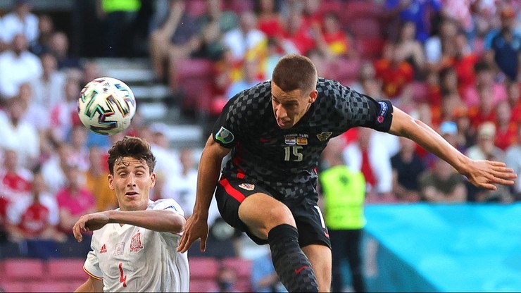 Piłkarz Chorwacji Mario Pa&scaron;alić w czarnej koszulce z numerem 15 pr&oacute;buje uderzyć głową piłkę lecącą w jego kierunku. Po lewej stronie, nisko pochylony, znajduje się młody piłkarz Hiszpanii w czerwonej koszulce z numerem 1, kt&oacute;ry r&oacute;wnież usiłuje dojść do piłki.