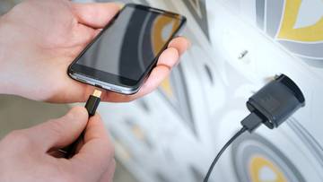 Ręka podłącza kabel ładowarki do smartfona.