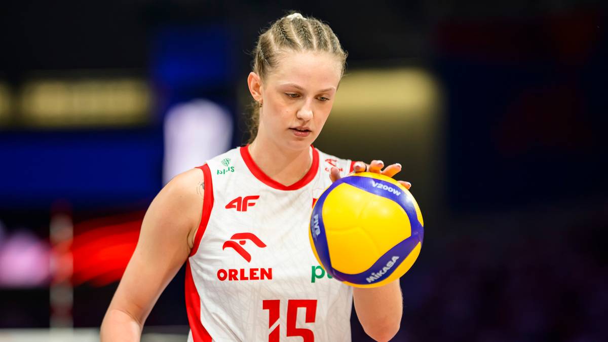 Siatkarka w białej koszulce z numerem 15 trzyma piłkę do siatk&oacute;wki.