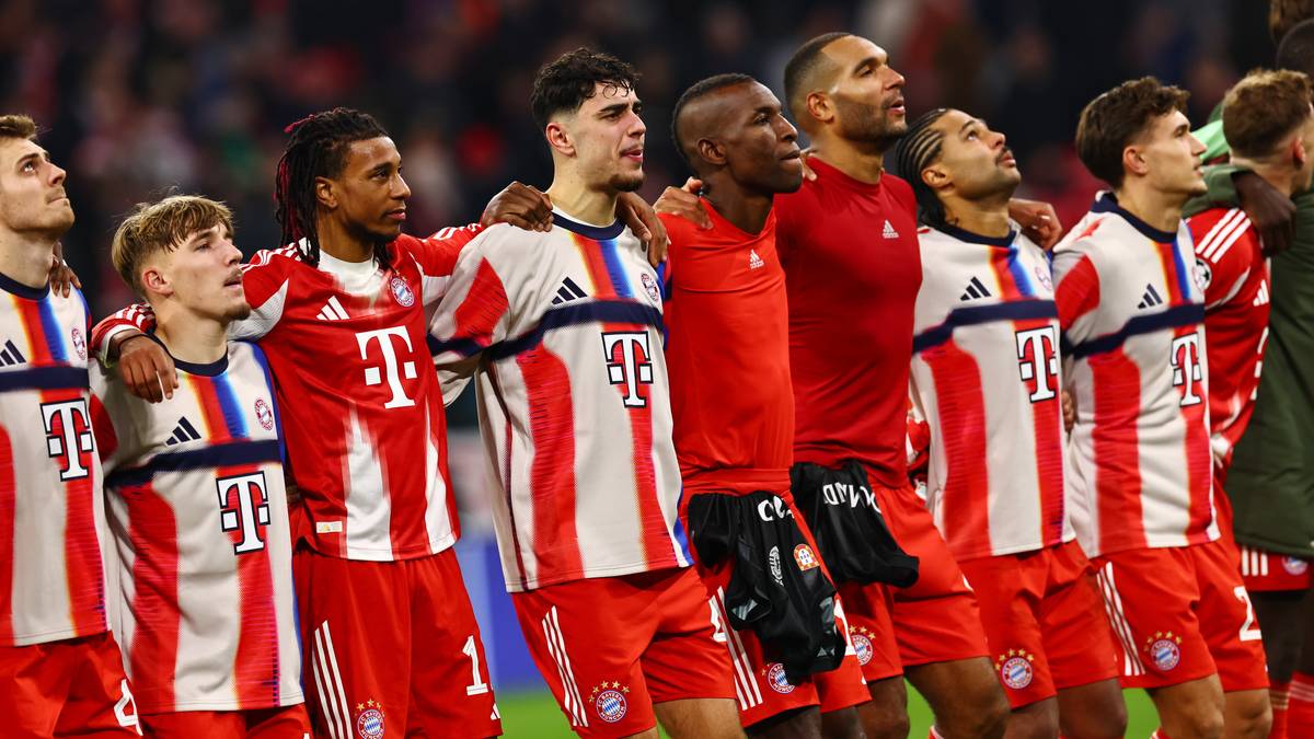 Piłkarze w czerwono-białych strojach stoją obok siebie, patrząc w górę.