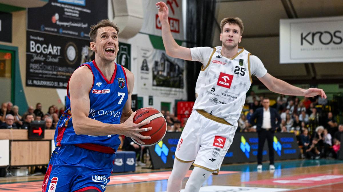 Koszykarz w niebieskim stroju z numerem 7 prowadzi piłkę i patrzy w kierunku przeciwnika. Koszykarz w białym stroju z numerem 25 znajduje się obok niego.