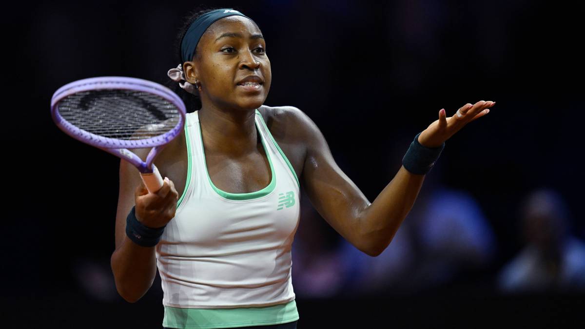 Coco Gauff trzyma rakietę tenisową i podnosi rękę w geście protestu lub zdziwienia podczas meczu.