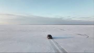 Samoch&oacute;d jedzie po zamarzniętej powierzchni z widocznymi śladami opon.