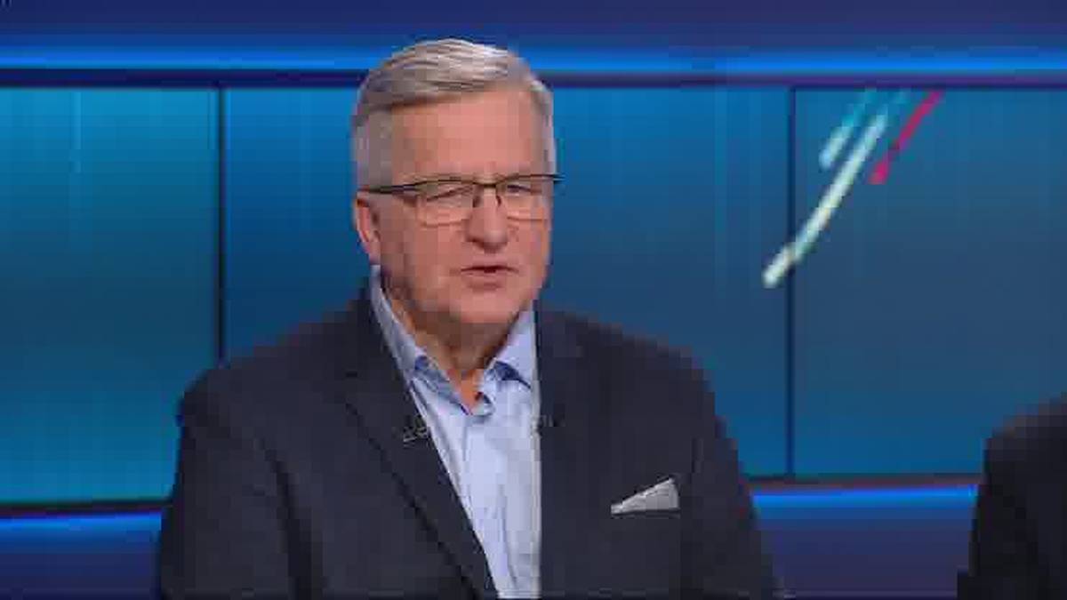 Mężczyzna w okularach i marynarce siedzi podczas debaty.